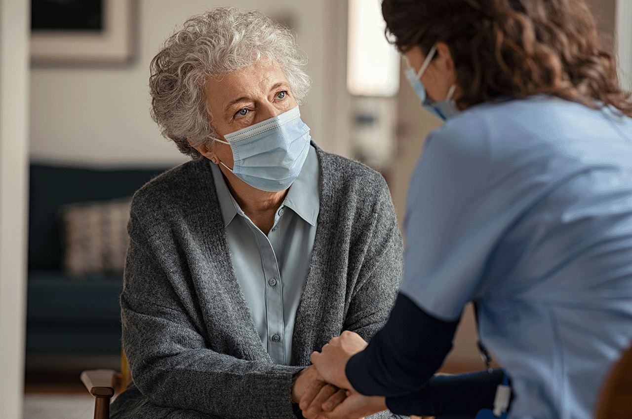 Older lady in mask talking to nurse