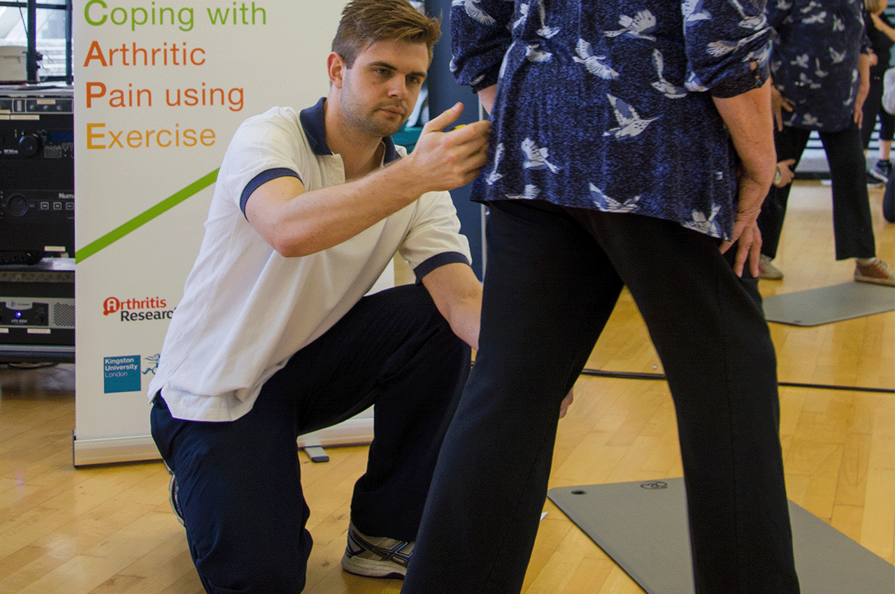 Physiotherapist kneeling on floor helping another person with exercises