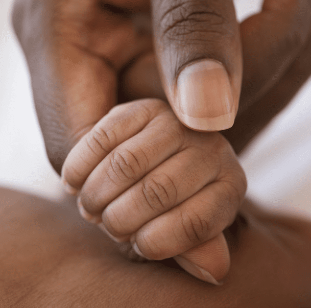 Baby's hand inter-twinned with adult hand