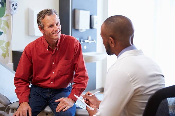 A male patient smiles at a male doctor during a consultation